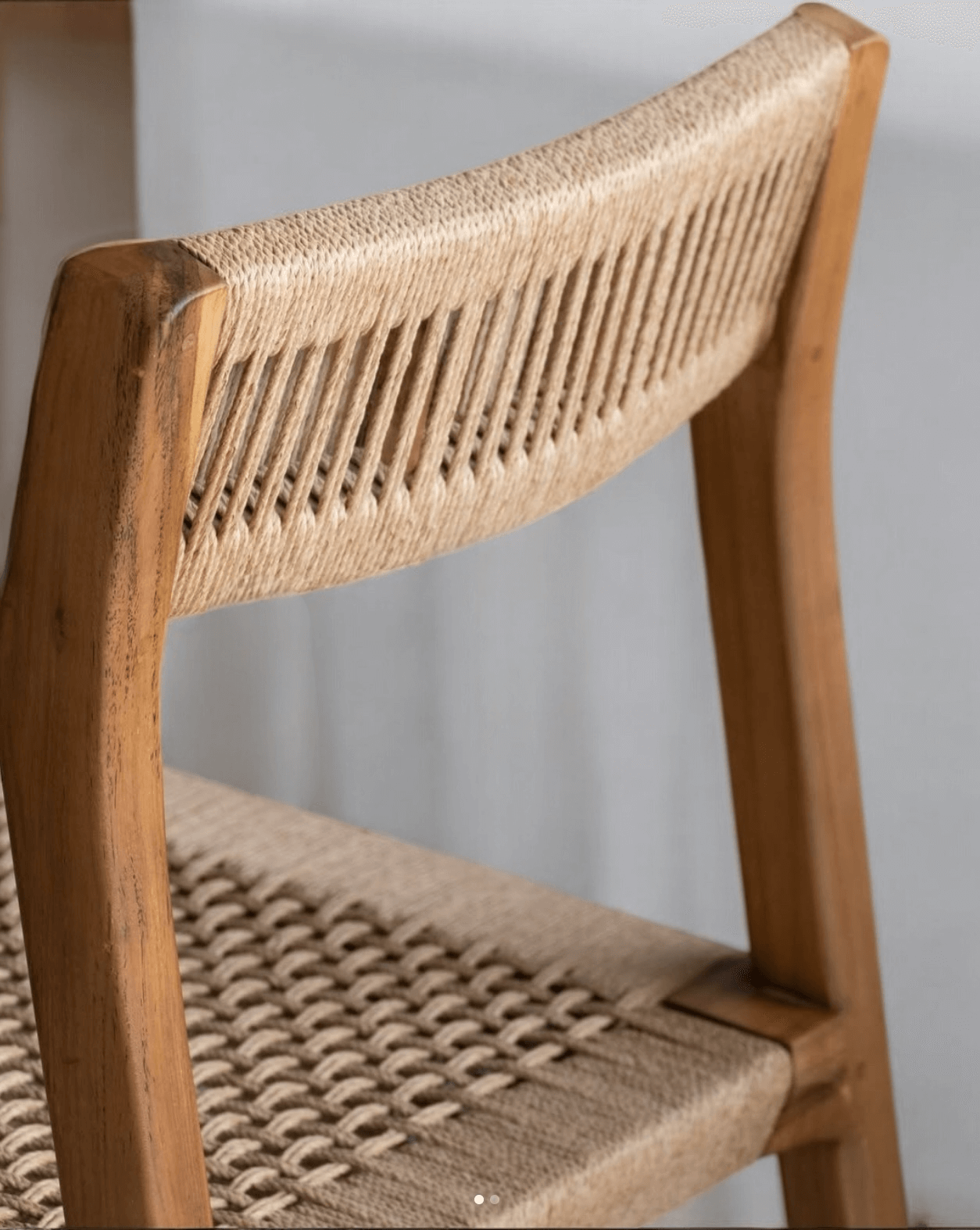Close-up of a teak dining chair showcasing the handwoven natural loom backrest and seat detailing.