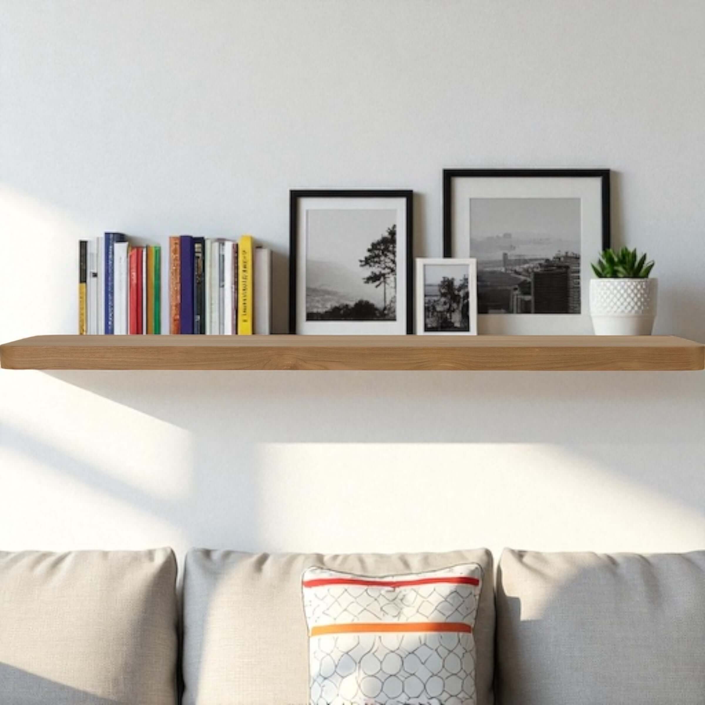 Reclaimed teak floating wall shelf styled with books and framed photos above a cozy couch.