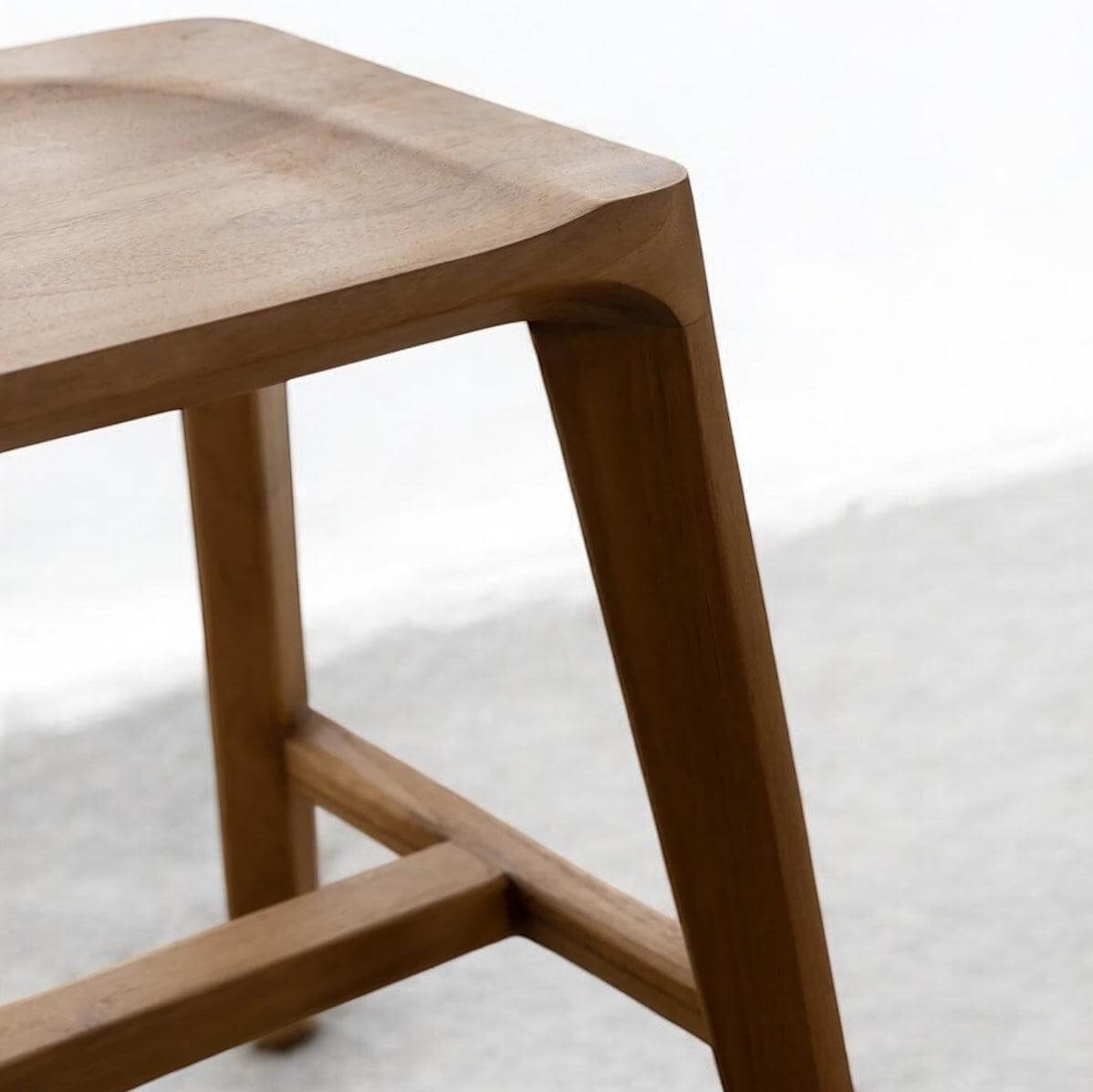 Close-up of a beautifully crafted recycled teak dining bench showcasing its smooth surface and elegant legs.