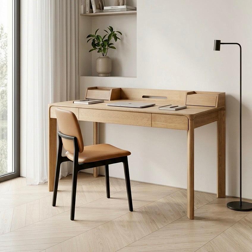 Glide teak desk with chair in a modern room with a plant and lamp.
